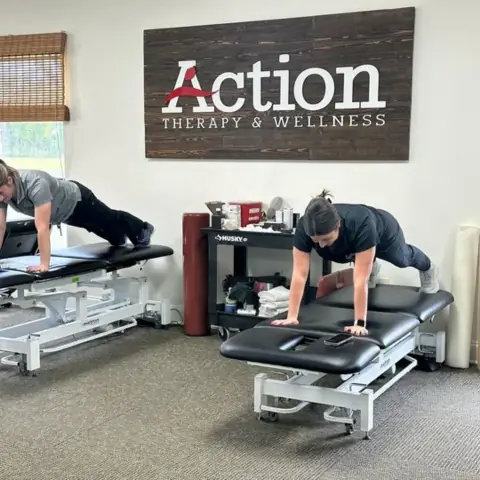 Two Action Therapy staff members holding plank positions on treatment tables in the Gonzales clinic